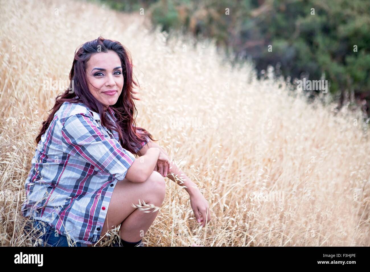 Portrait of mid adult woman sitting in long grass Banque D'Images