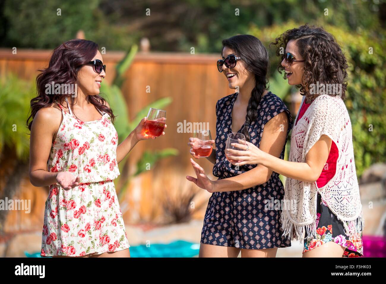 Trois sœurs adultes commérage et boire vin rose de jardin Banque D'Images