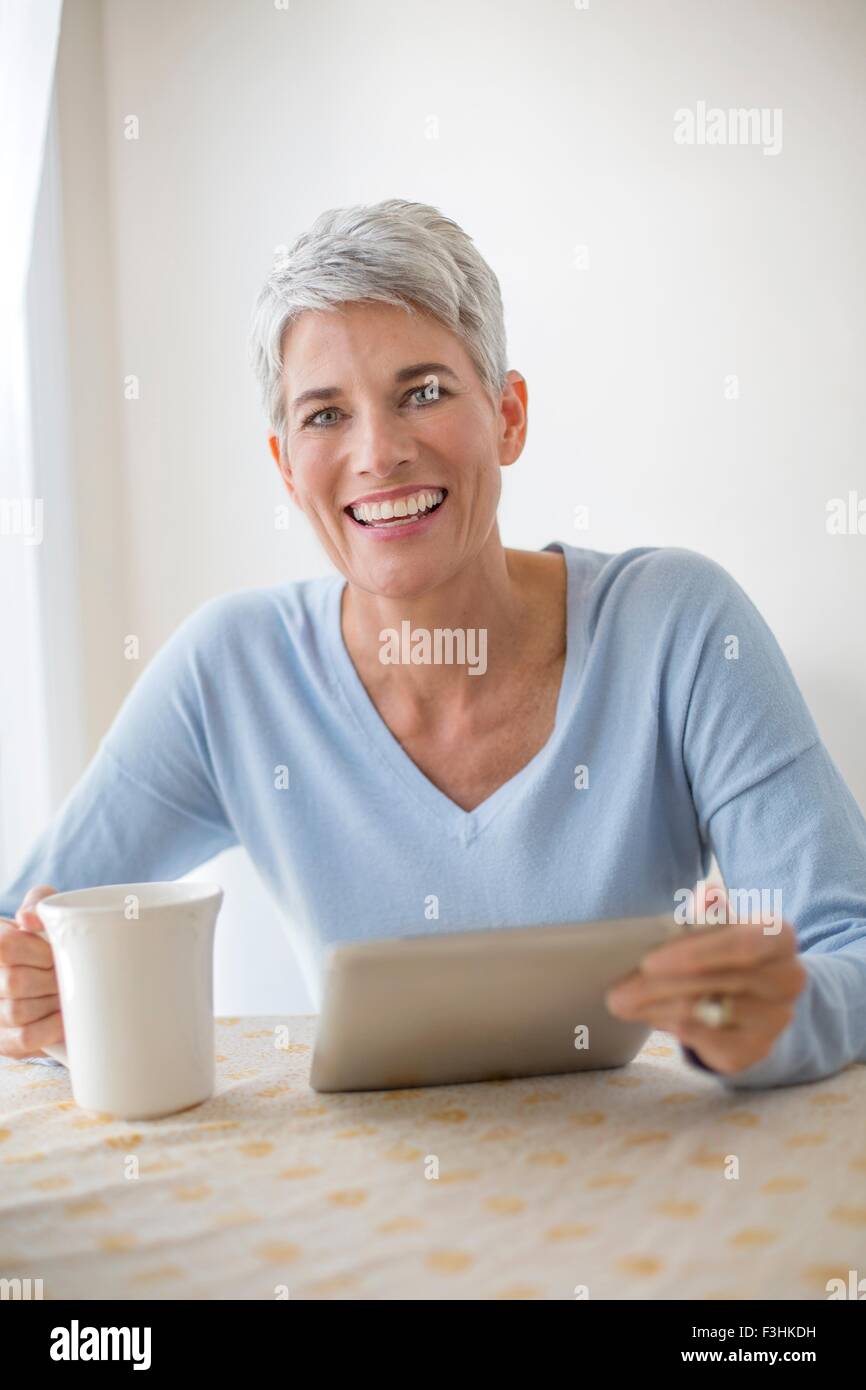 Portrait de femme mature aux cheveux gris avec des yeux bleus using digital tablet Banque D'Images