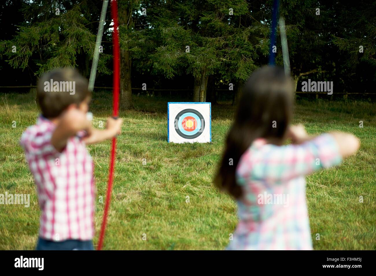 Vue arrière du frère et sœur adolescente practicing archery Banque D'Images