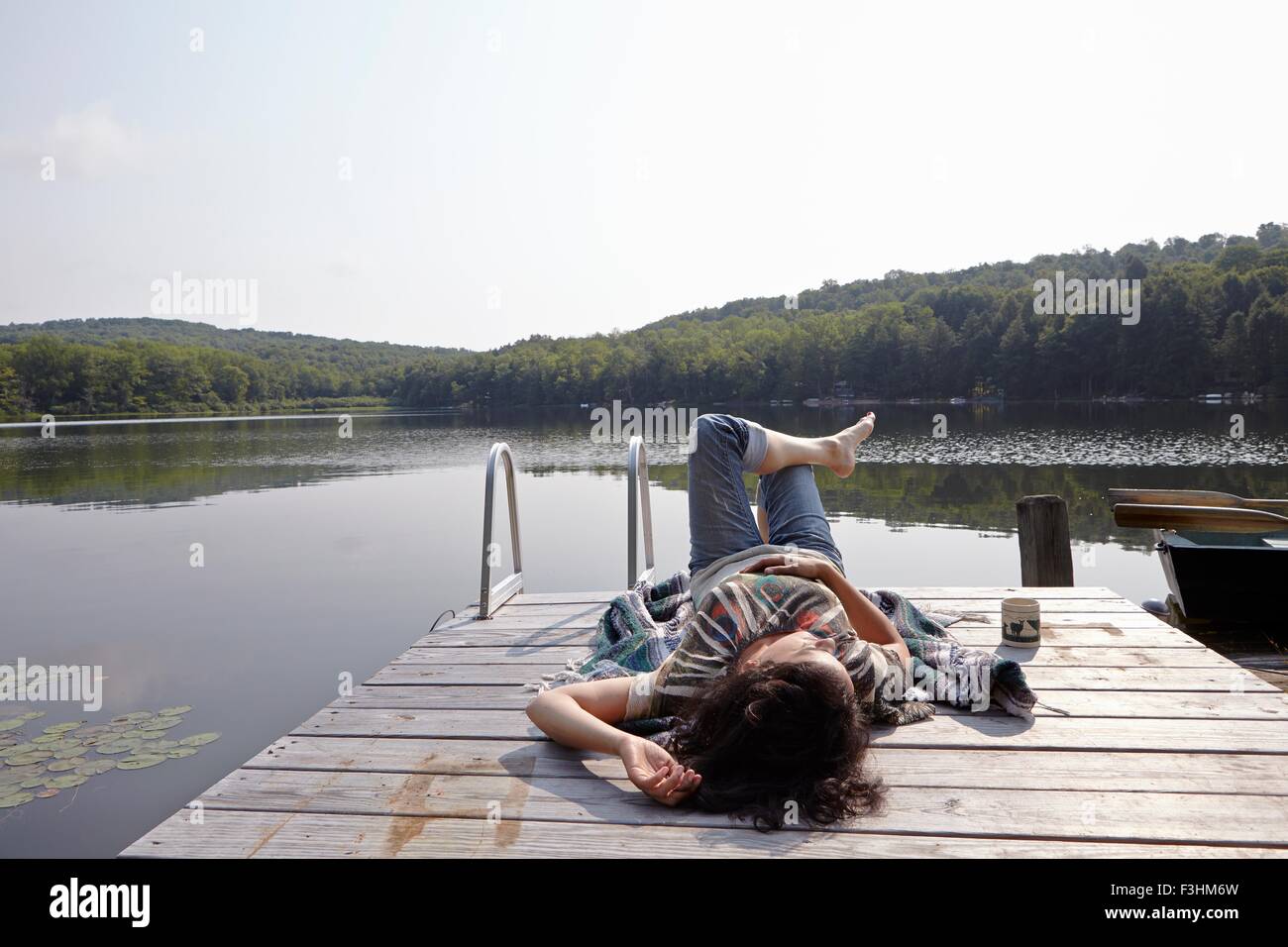 Woman relaxing on lake pier, New Milford, New Jersey, USA Banque D'Images