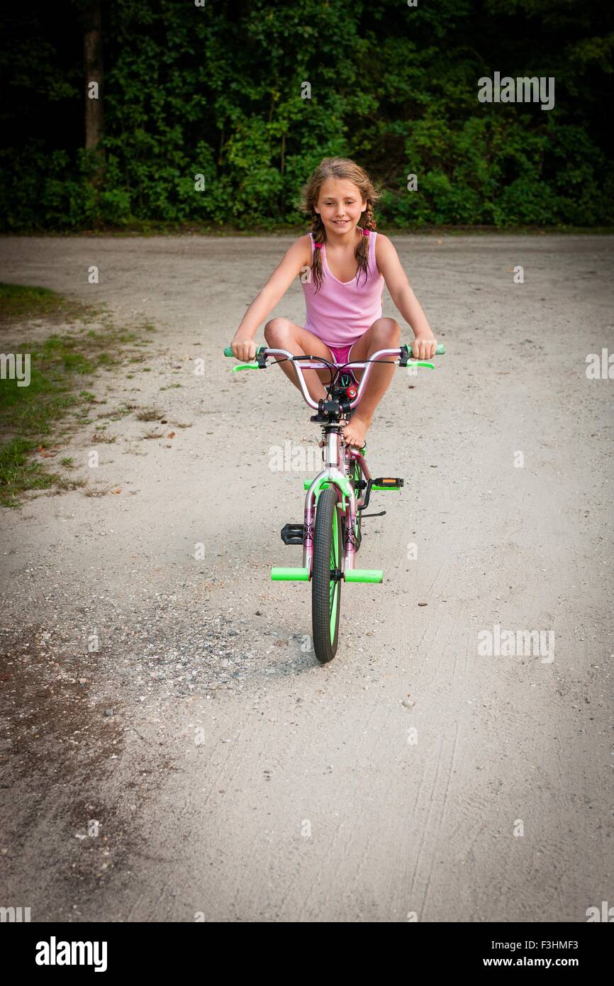 Vue avant d'équilibrage fille à vélo, les jambes soulevées, smiling Banque D'Images