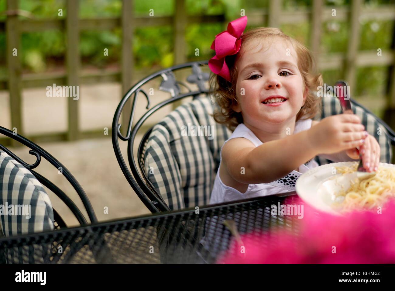 Au jardin, table de salle à manger girl looking at camera smiling Banque D'Images