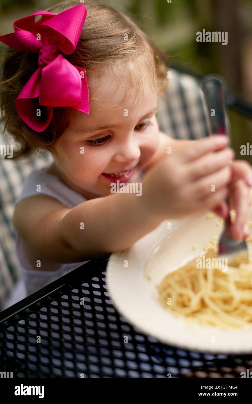 High angle vew de fille aux cheveux roses assise à bow garden mange du spaghetti Banque D'Images