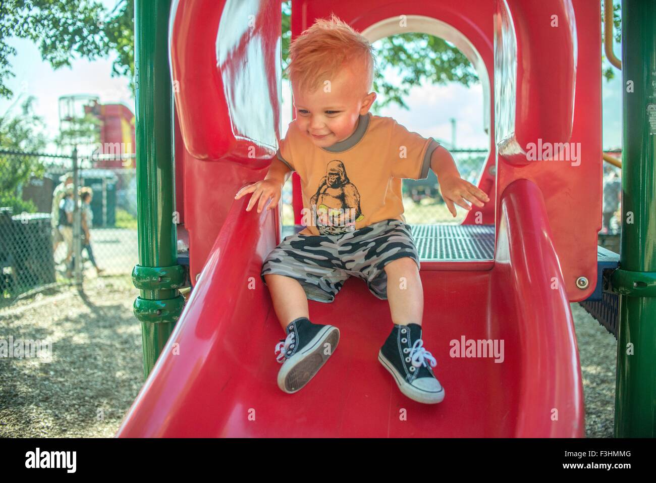 Un bébé garçon jouant sur l'aire rouge slide Banque D'Images