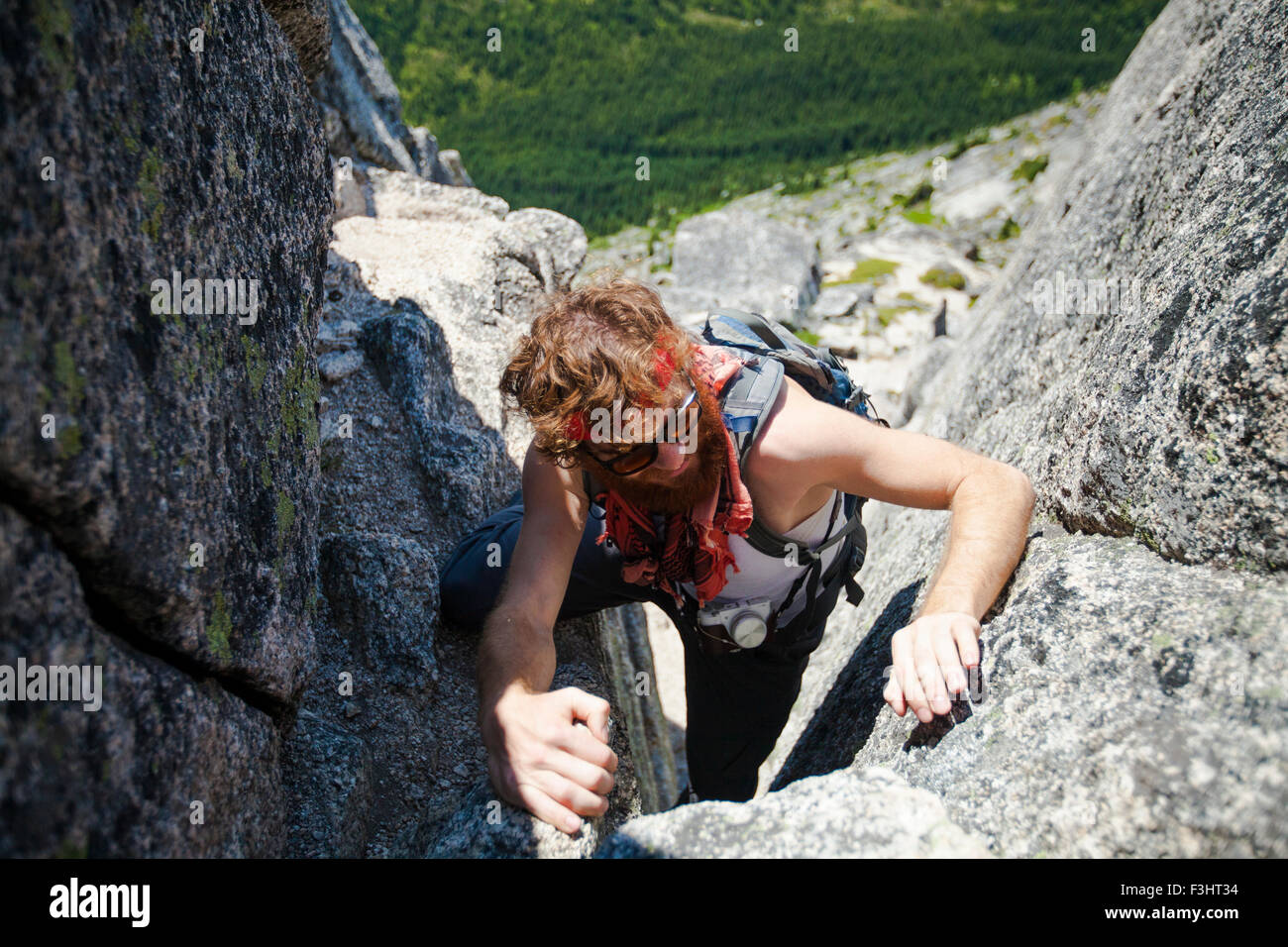 Un randonneur grimpe une roche de granit cheminée en route de pointe de l'aiguille Banque D'Images