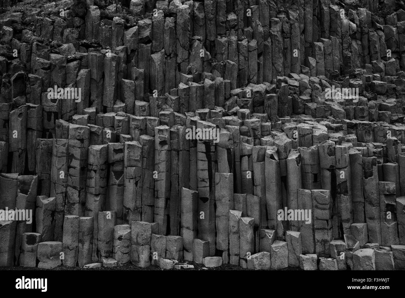 Des formations de roche de basalte colonne géométrique sur la plage volcanique de sable noir Kirkjufjara près de Vik, Islande Banque D'Images