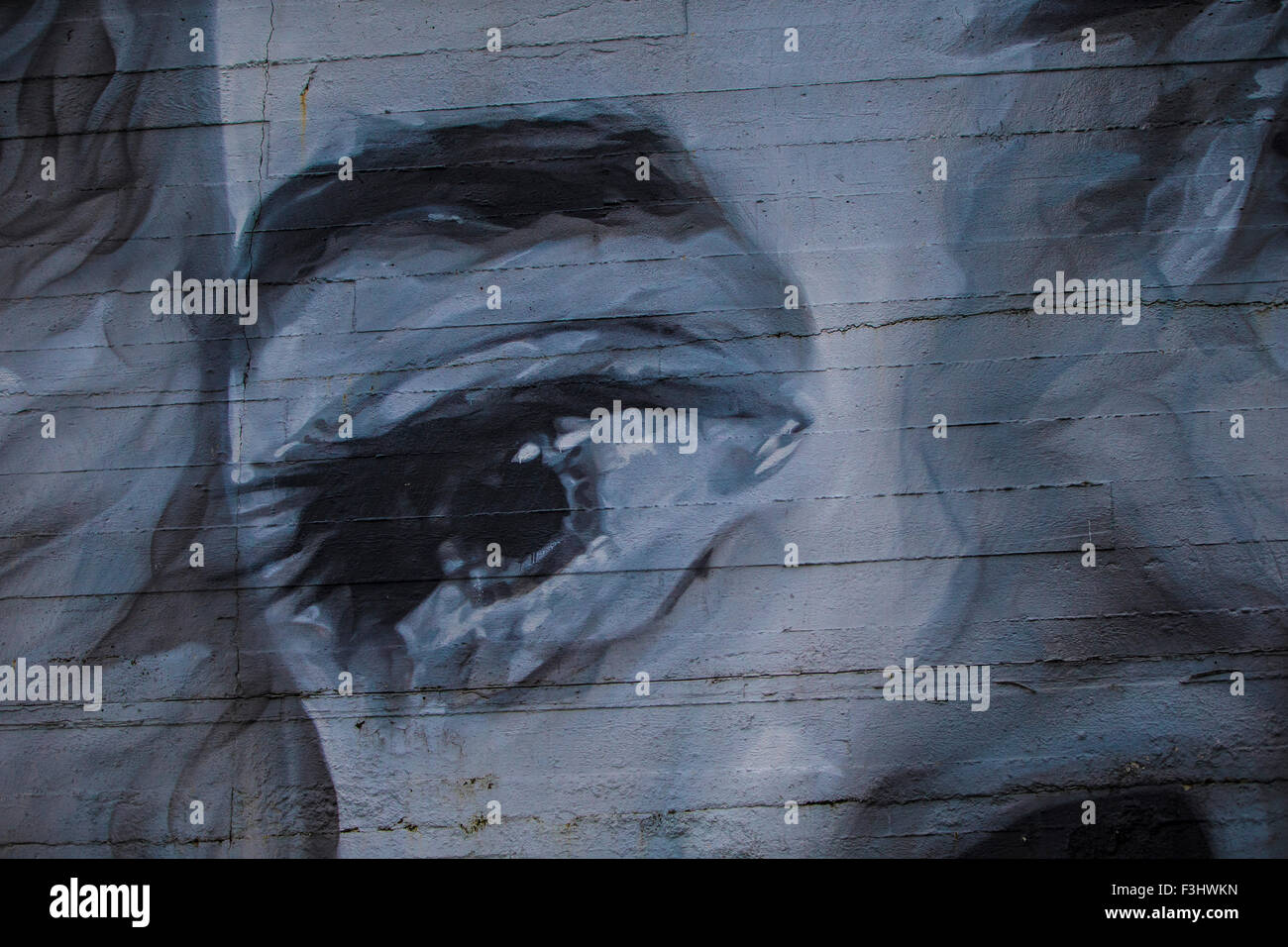 Un grand œil mesdames peint graffiti peint sur la fissuration d'un mur de béton blanc et de Banque D'Images