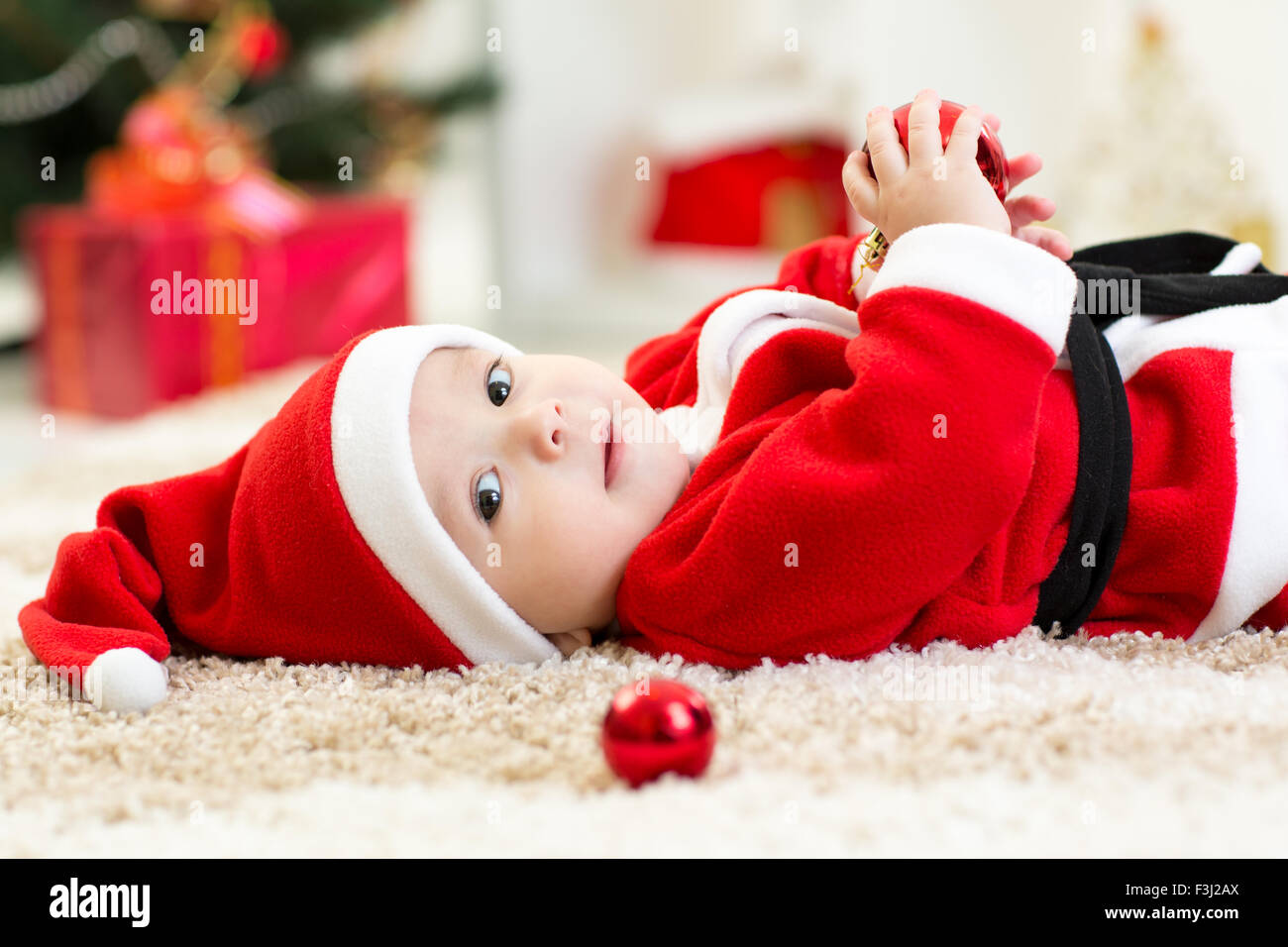 Baby Boy portée Santa situées près de l'arbre de Noël Banque D'Images
