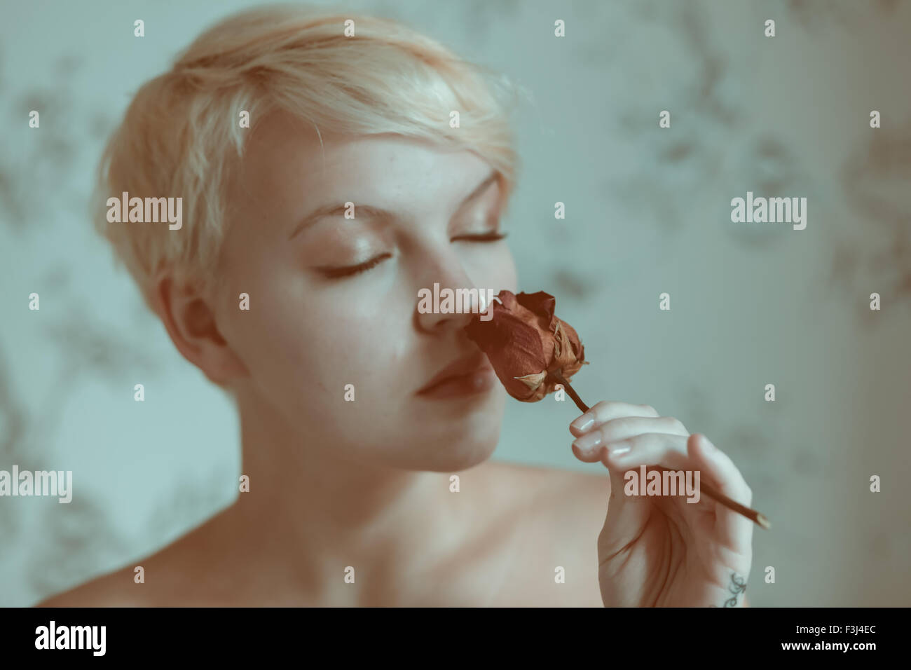 Blonde teenage girl holding a dead rose Banque D'Images