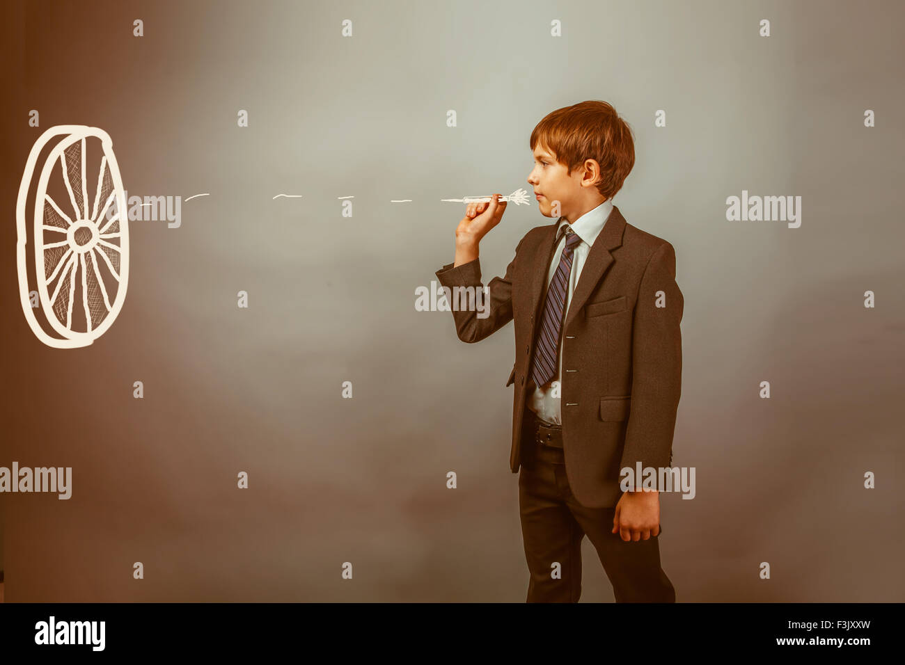 Teen boy businessman lançant des fléchettes sur une cible fléchette sur un fond bleu b Banque D'Images