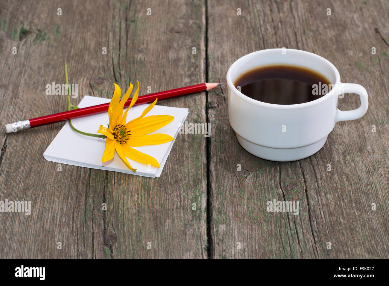 Still Life tasse de café, papier, crayon et carte de souhaits, fleur jaune Banque D'Images