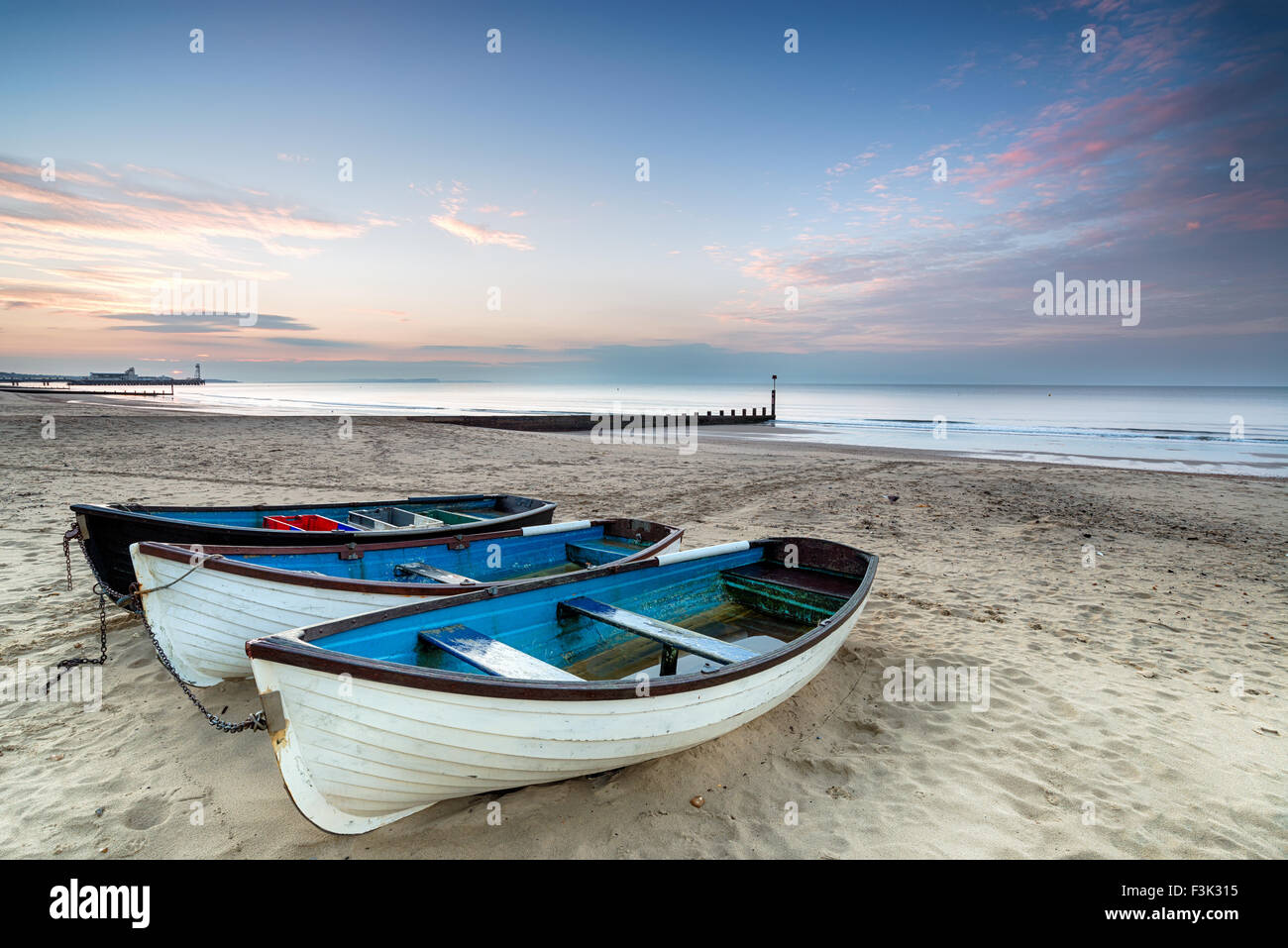 Le lever du soleil sur les bateaux de pêche sur la plage de Bournemouth Banque D'Images