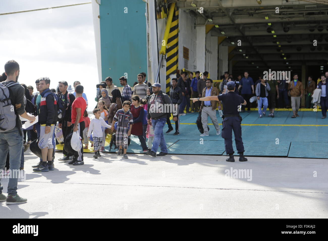 Le Pirée, Grèce. 05Th Oct, 2015. Un agent de police dirige les réfugiés du ferry pour les autobus qui va les amener à la station de métro au Pirée. Le ferry El. Venizelos a apporté 2 500 des réfugiés de l'île grecque de Lesbos au Pirée. Les réfugiés sont ensuite portés par les autobus de la station de métro, d'où ils voyageront dans l'Athènes et plus tard sur d'autres vers l'Europe occidentale. Le ferry est l'un des trois affrétés par le gouvernement grec pour le transport des réfugiés de l'îles grecques à Athènes sur une base continue. © Michael Debets/Pacific Press/Alamy Live News Banque D'Images