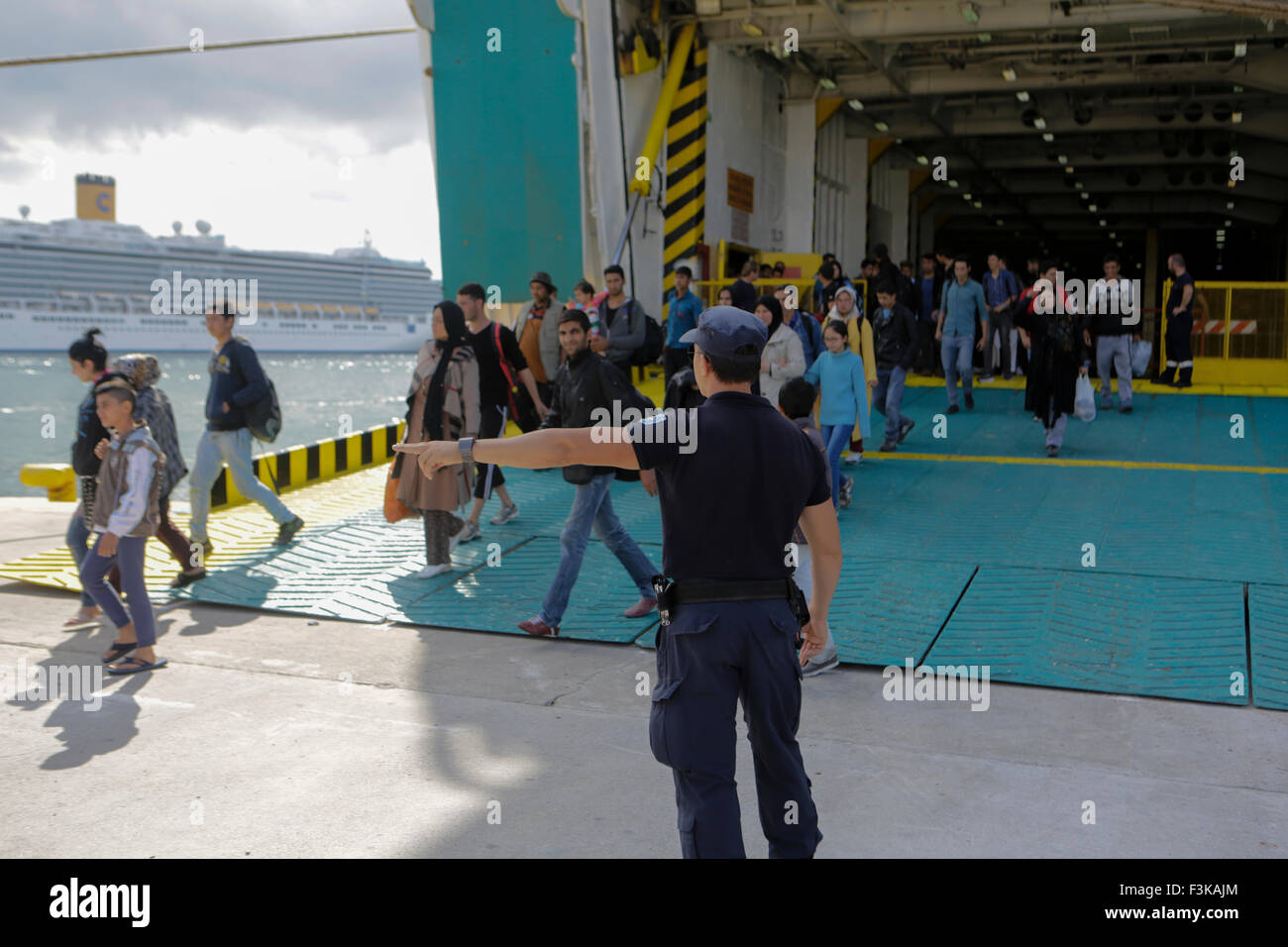 Le Pirée, Grèce. 05Th Oct, 2015. Un agent de police dirige les réfugiés du ferry pour les autobus qui va les amener à la station de métro au Pirée. Le ferry El. Venizelos a apporté 2 500 des réfugiés de l'île grecque de Lesbos au Pirée. Les réfugiés sont ensuite portés par les autobus de la station de métro, d'où ils voyageront dans l'Athènes et plus tard sur d'autres vers l'Europe occidentale. Le ferry est l'un des trois affrétés par le gouvernement grec pour le transport des réfugiés de l'îles grecques à Athènes sur une base continue. © Michael Debets/Pacific Press/Alamy Live News Banque D'Images