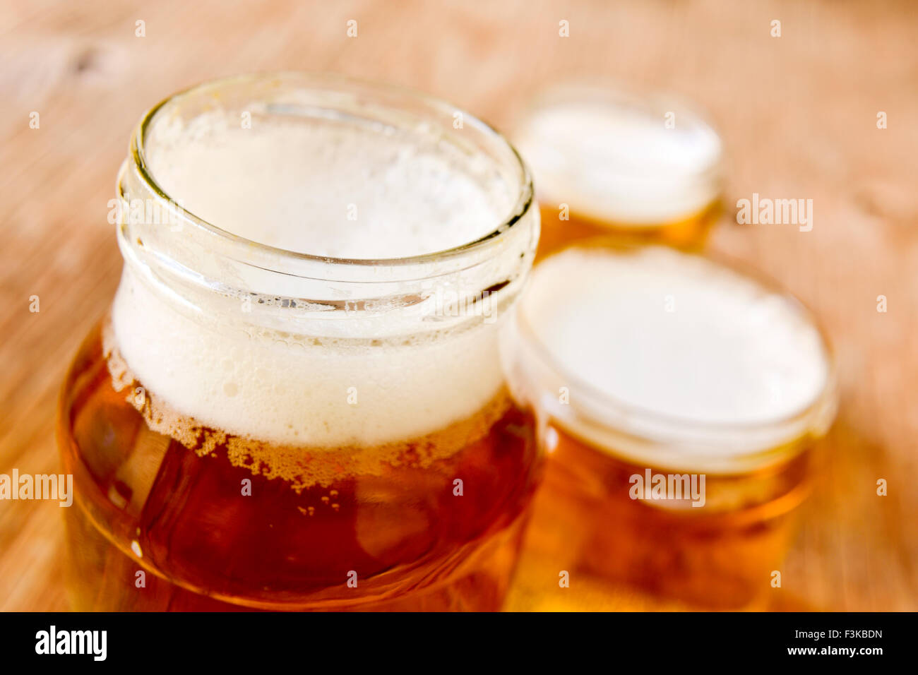 Bière servie dans des bocaux en verre sur une surface en bois rustique Banque D'Images