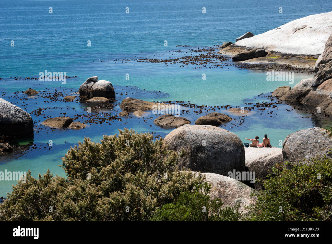 Couple assis sur le rocher surplombant l'océan, la plage de Boulders National Park, Simonstown, Afrique du Sud Banque D'Images