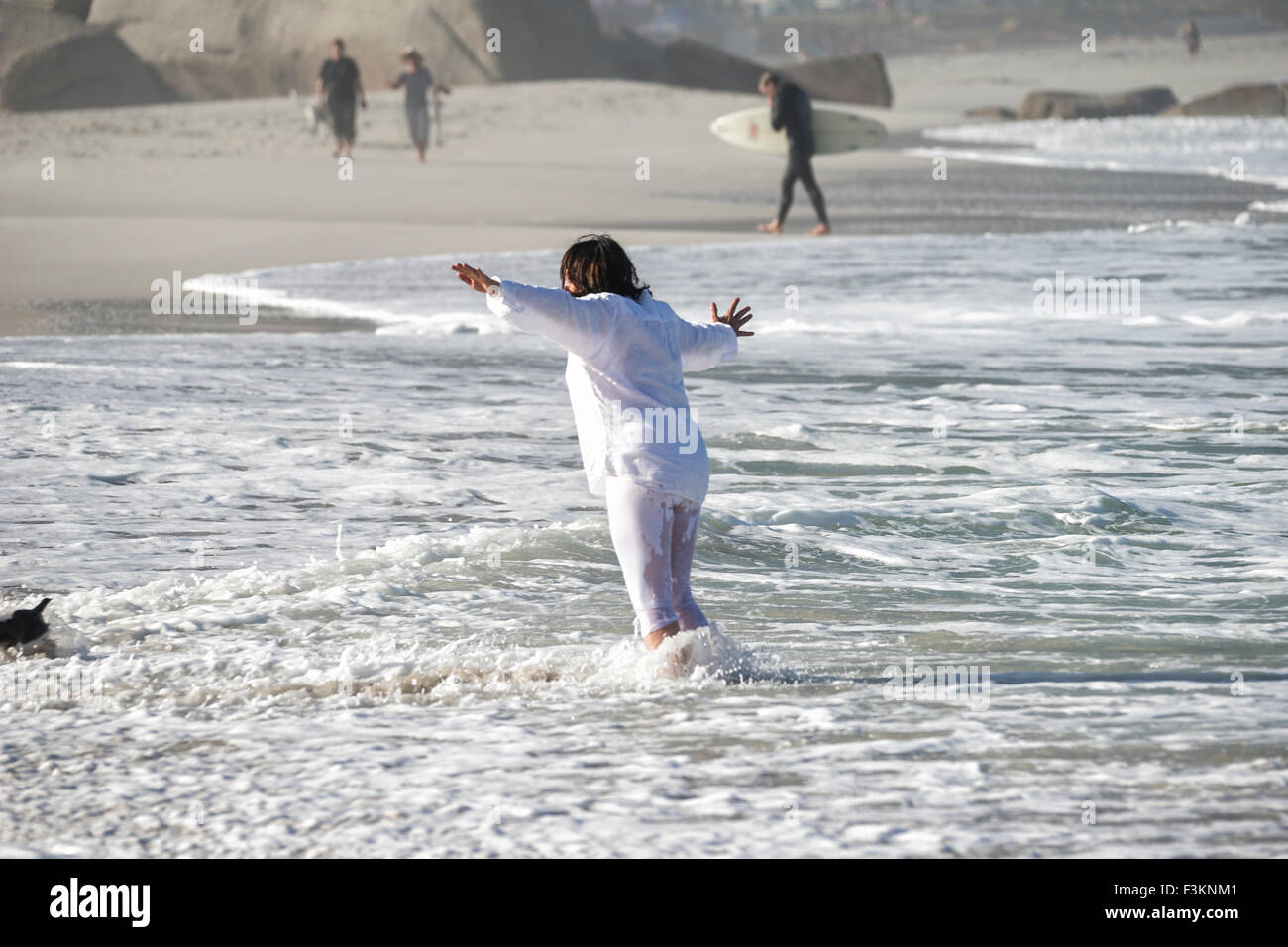 Les vagues déferlent en une femme portant des vêtements blancs à Camp's Bay Beach, l'océan Atlantique, Cape Town, Afrique du Sud Banque D'Images