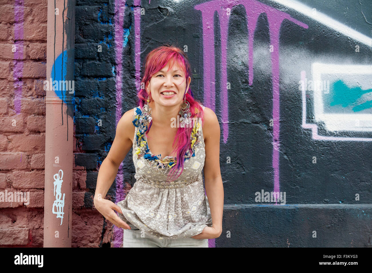 Jeune fille belle à Harajuku style avec les cheveux colorés et freaky outfit en face du mur avec peinture d'art de rue Banque D'Images