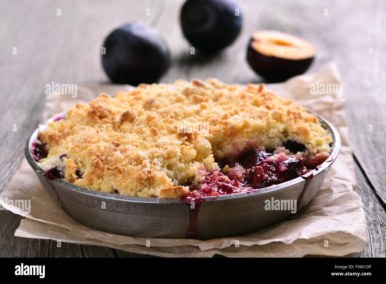 Tarte aux prunes crumb dans le moule, sur fond de bois Banque D'Images