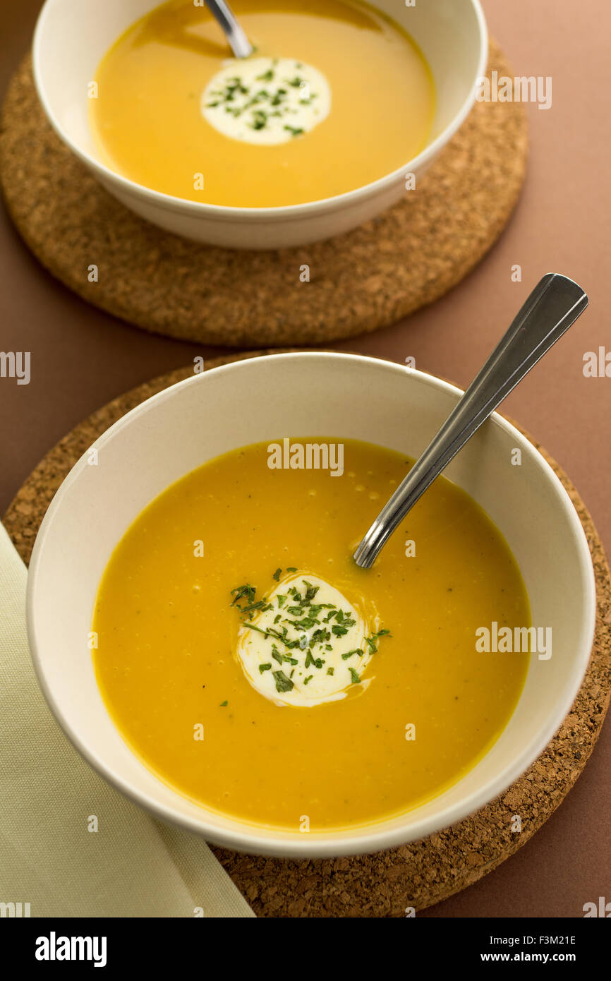 Soupe de potiron chaude avec de la crème et garnir de persil servi dans des bols en céramique ronde Banque D'Images
