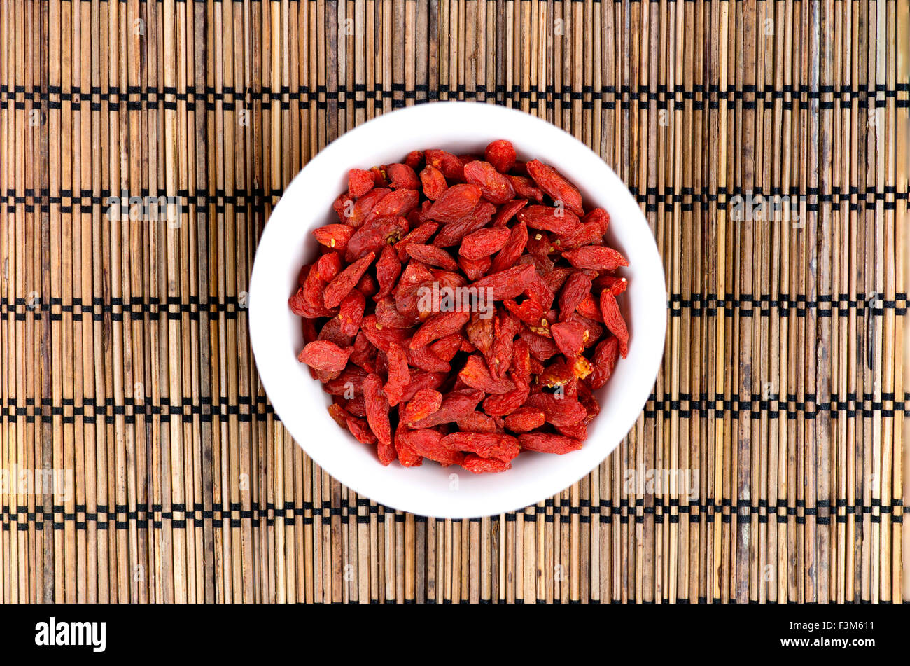 Les baies de goji dans un bol blanc sur le tapis oriental Banque D'Images