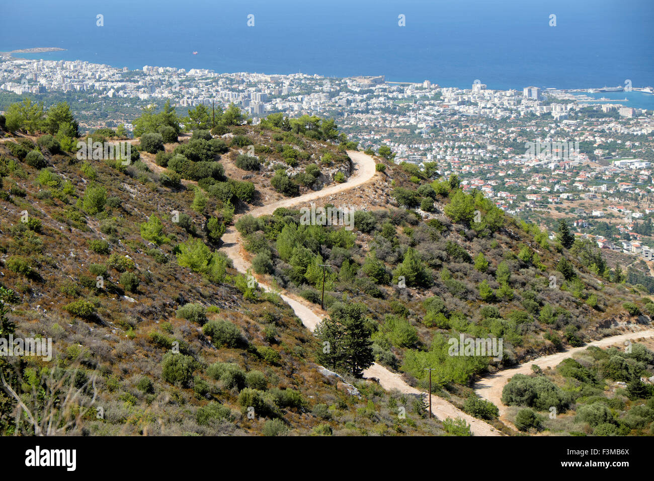 Paysage aride et winding road trail sur une colline avec une vue sur la mer et la ville côtière de port de Kyrenia, dans le nord de Chypre KATHY DEWITT Banque D'Images