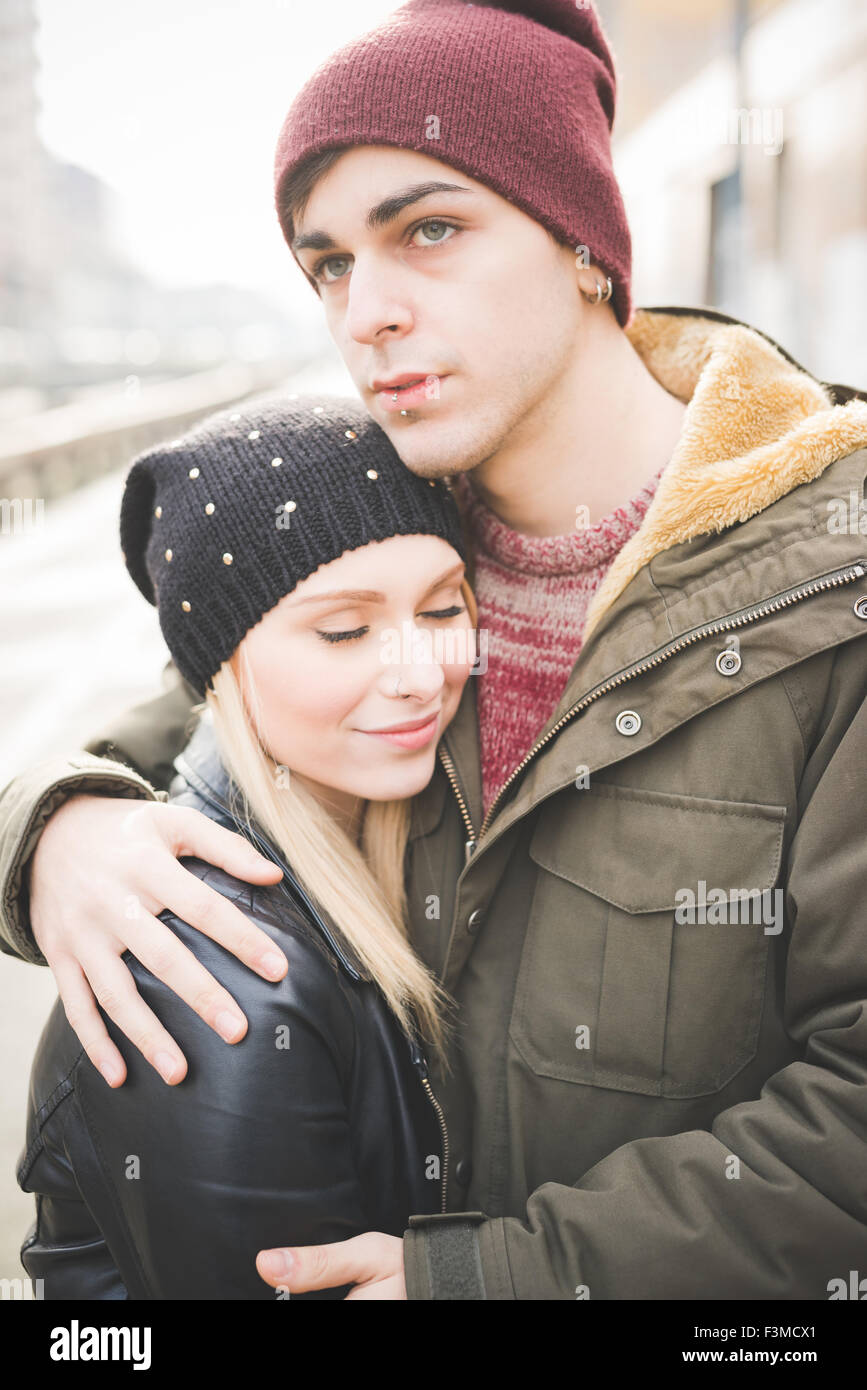 Belle jeune femme blonde et les yeux bleus, les amoureux des homme couple hugging dans la rue - elle est les yeux fermés, il est donnant sur la droite - l'amour, confiance, Banque D'Images