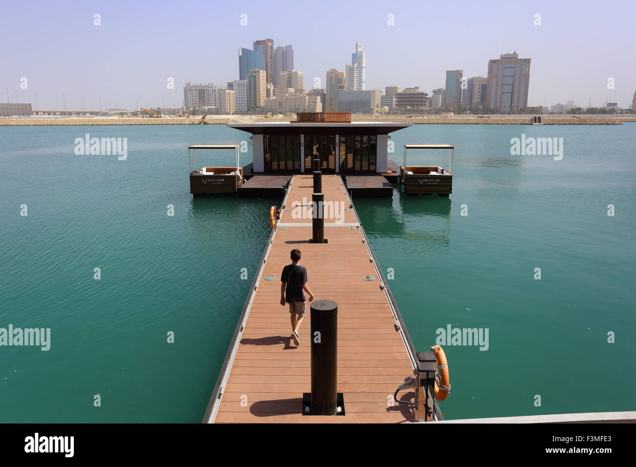 Garçon marchant le long de la jetée de l'hôtel Four Seasons, Royaume de Bahreïn Banque D'Images