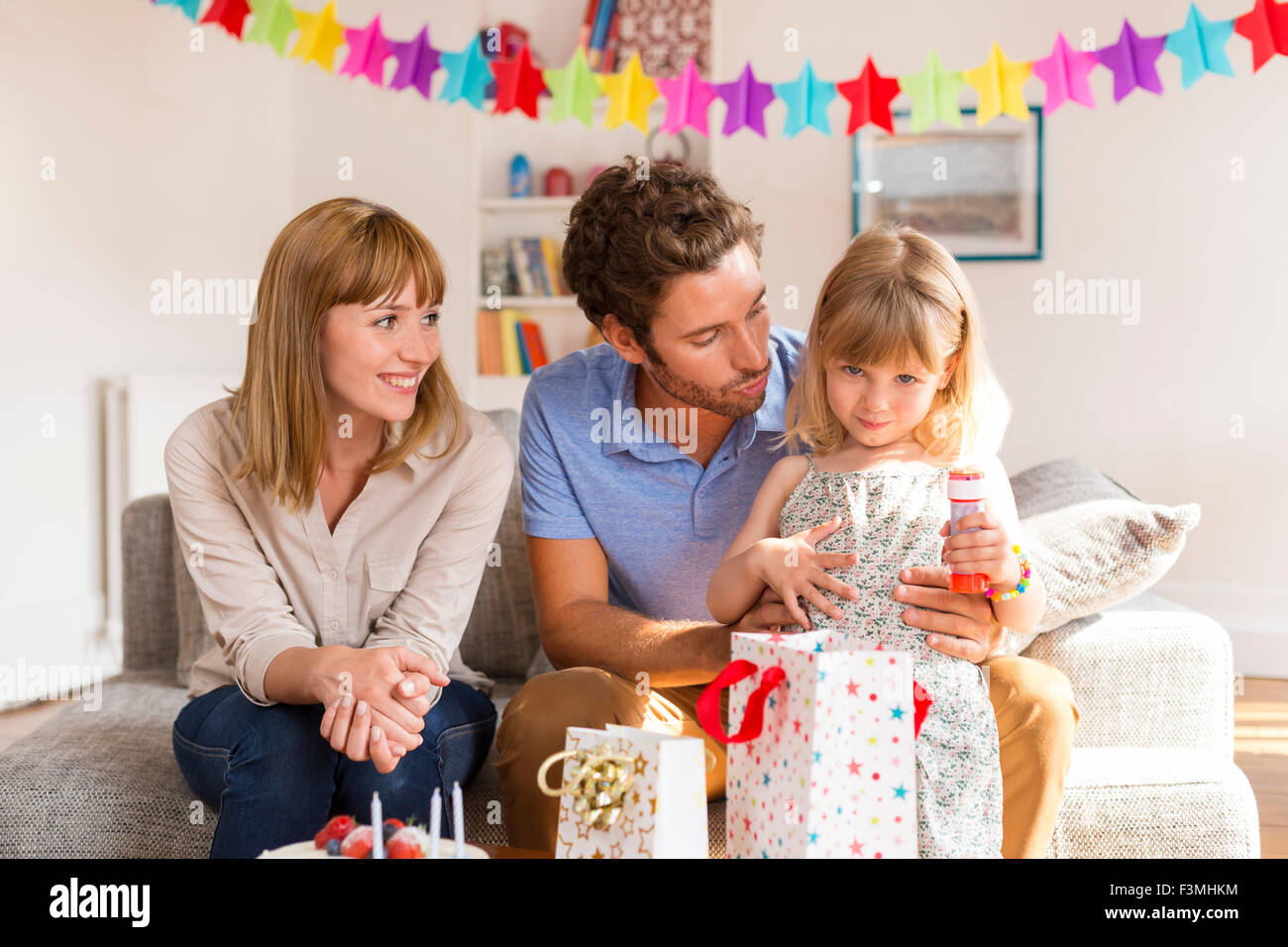 Petite fille fête d'anniversaire en maison moderne avec ses parents. Looking at camera Banque D'Images