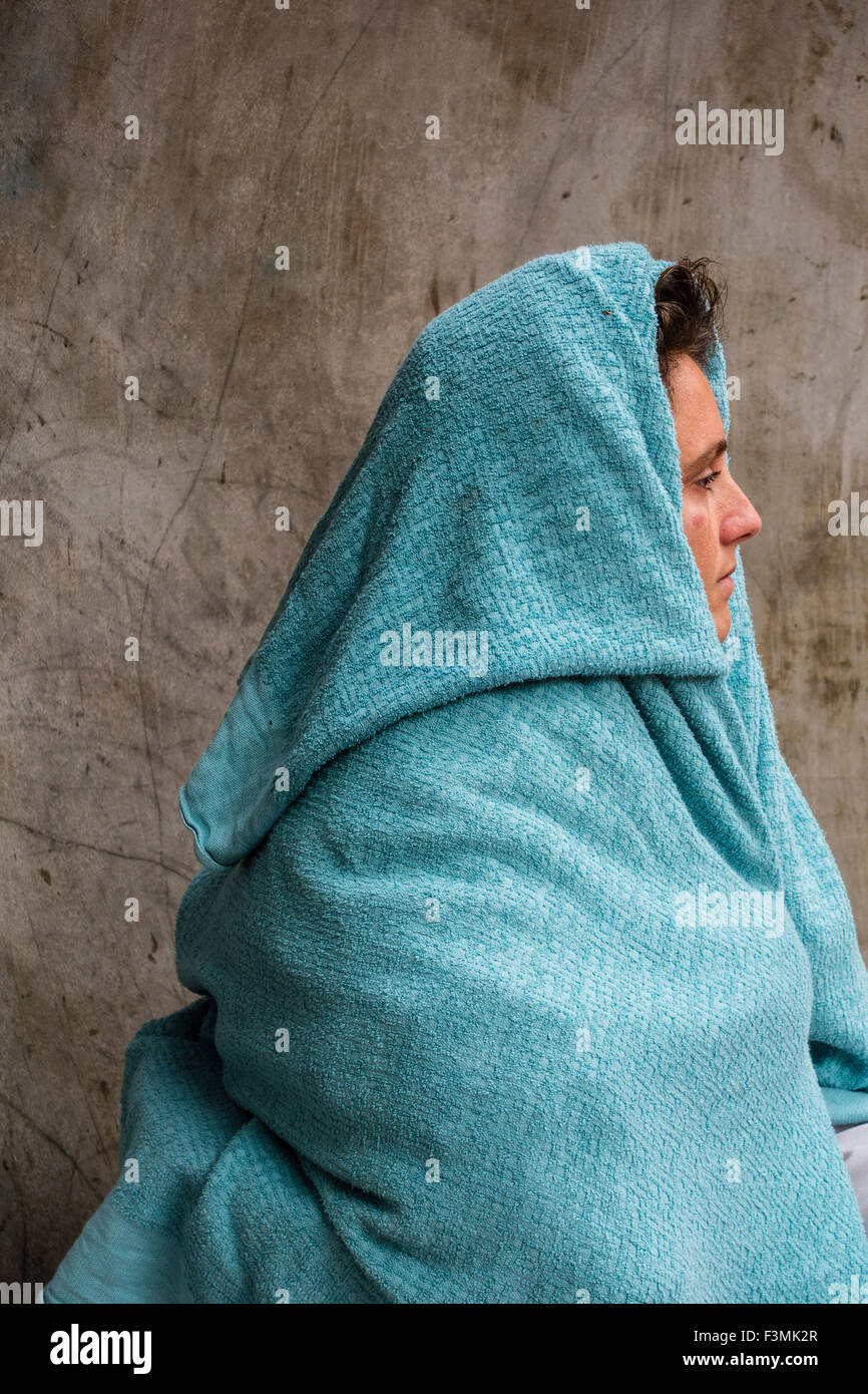Une femme sans-abri est assis sur un banc dans le centre-ville de San Francisco avec une couverture qui couvre sa tête et ses épaules. Banque D'Images
