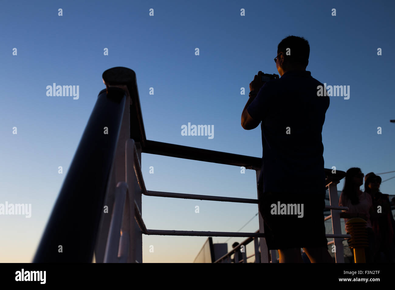 Counterlight photo de quelqu'un de prendre une photo du coucher du soleil à bord d'un navire de croisière Banque D'Images