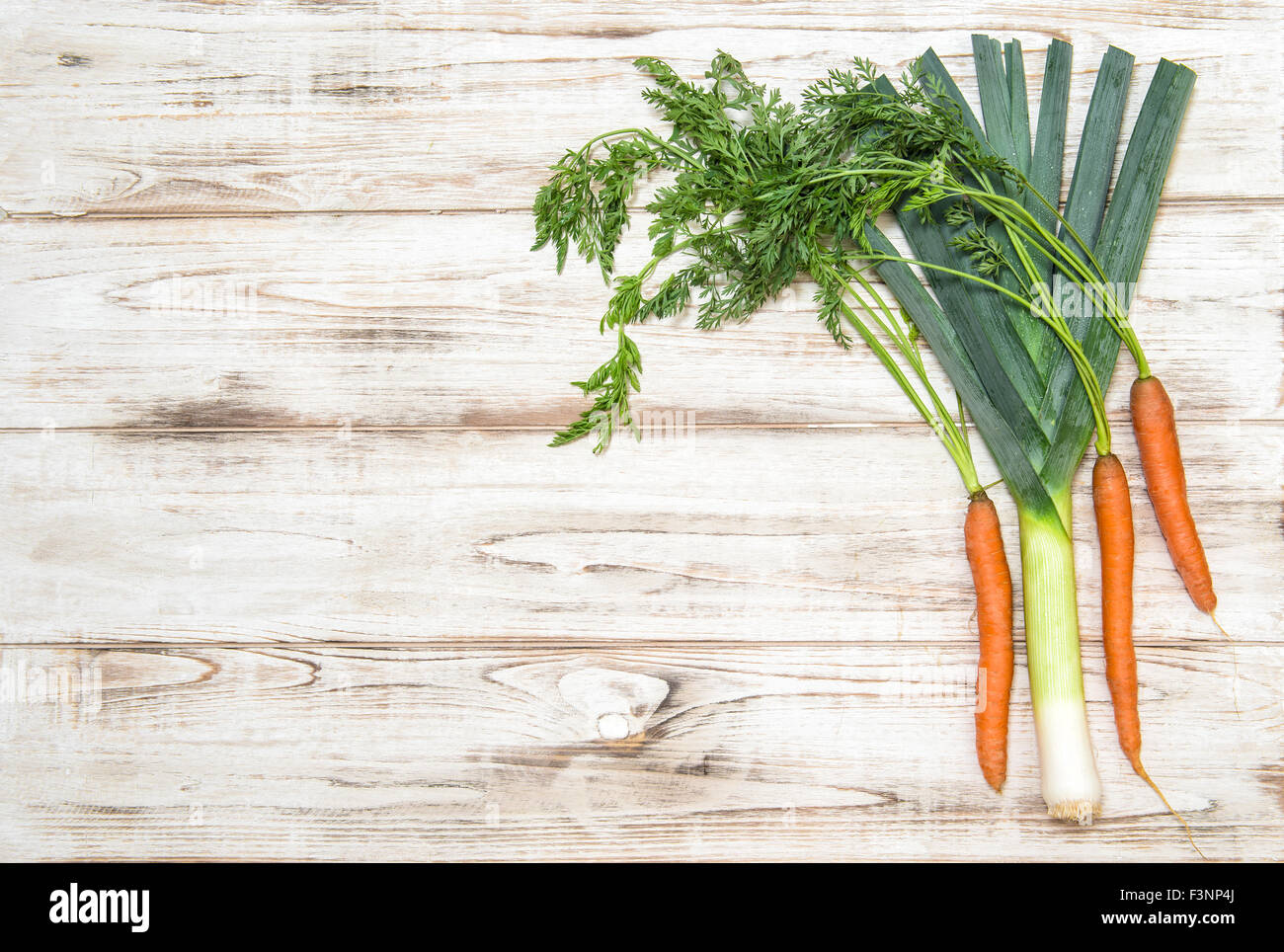 Les légumes frais biologiques. Le poireau et les carottes sur fond de bois. Ingrédients alimentaires sains Banque D'Images