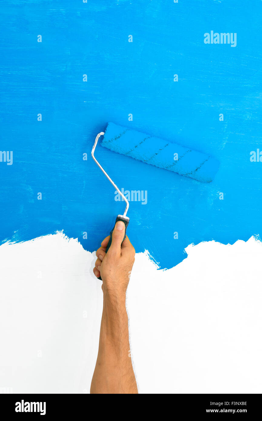 Peindre un mur à l'aide d'un rouleau avec de la peinture bleu Banque D'Images