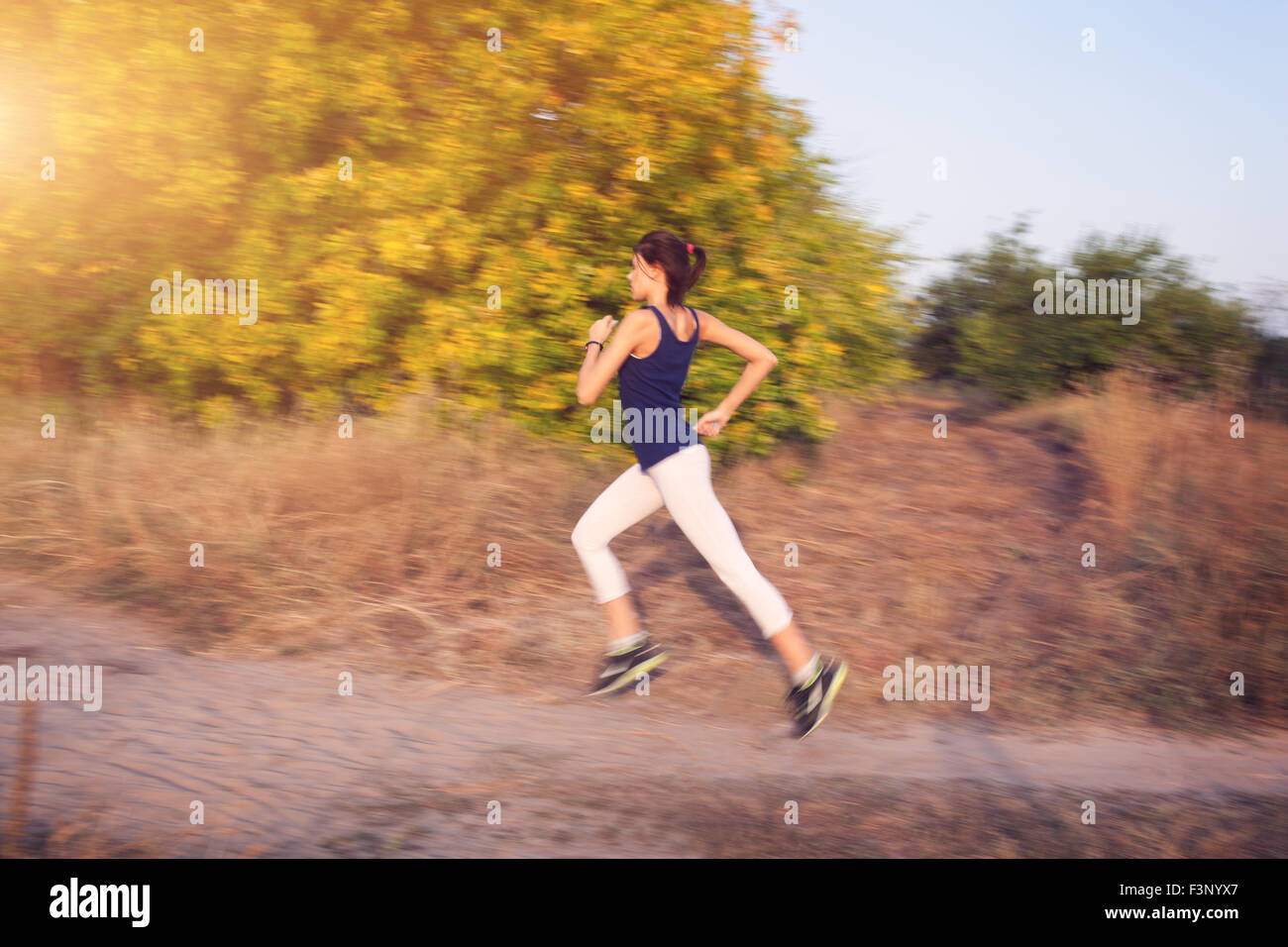 Jeune femme tournant sur un chemin rural au coucher du soleil dans la forêt d'automne. Fond sports Lifestyle Banque D'Images