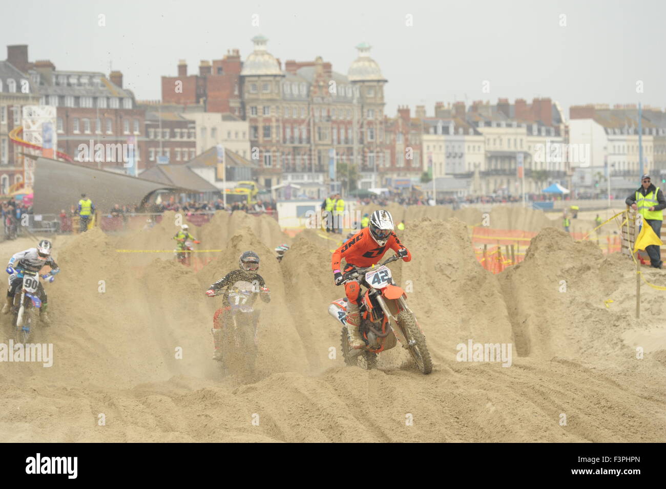 Weymouth, Dorset, UK - 11 octobre 2015. Lion's Beach annuel week-end de motocross sur plage de Weymouth. Weymouth et Portland Lion's organisent conjointement l'événement populaire avec club de motocross de Purbeck qui attire des centaines de coureurs, dont le test eux-mêmes sur la plage difficile course - Riders en compétition sur le parcours avec l'arrière-plan spectaculaire front de mer de Weymouth - Photo : Graham Hunt/Alamy Live News Banque D'Images