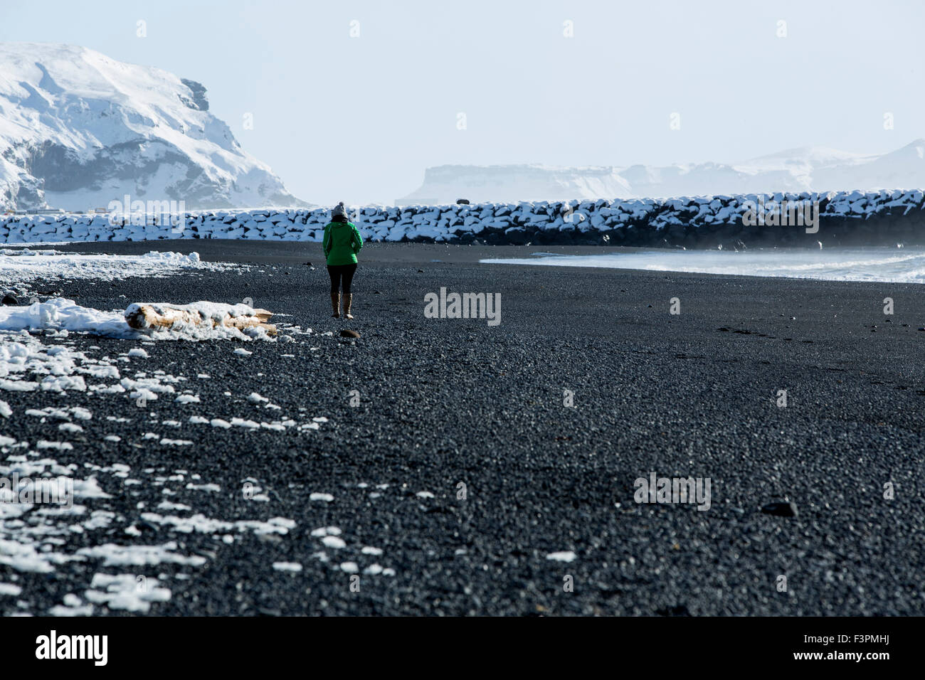 Femme marche le long de la plage de sable noir de Vik, l'Islande en hiver Banque D'Images