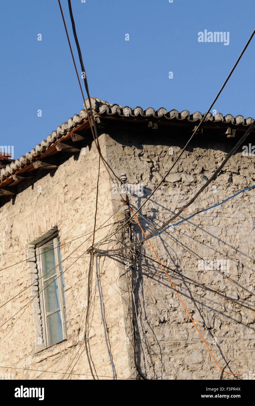 Un faisceau de câbles d'électricité et de téléphone de nombreux attachés à une maison dans le site du patrimoine mondial de Mangalemi, Berat Banque D'Images