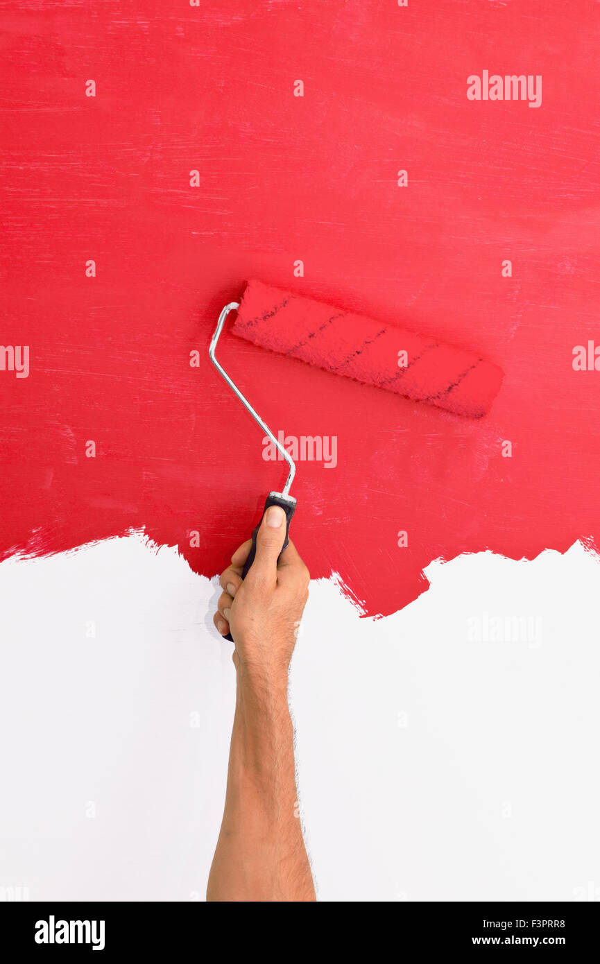 Peindre un mur à l'aide d'un rouleau avec de la peinture rouge Banque D'Images