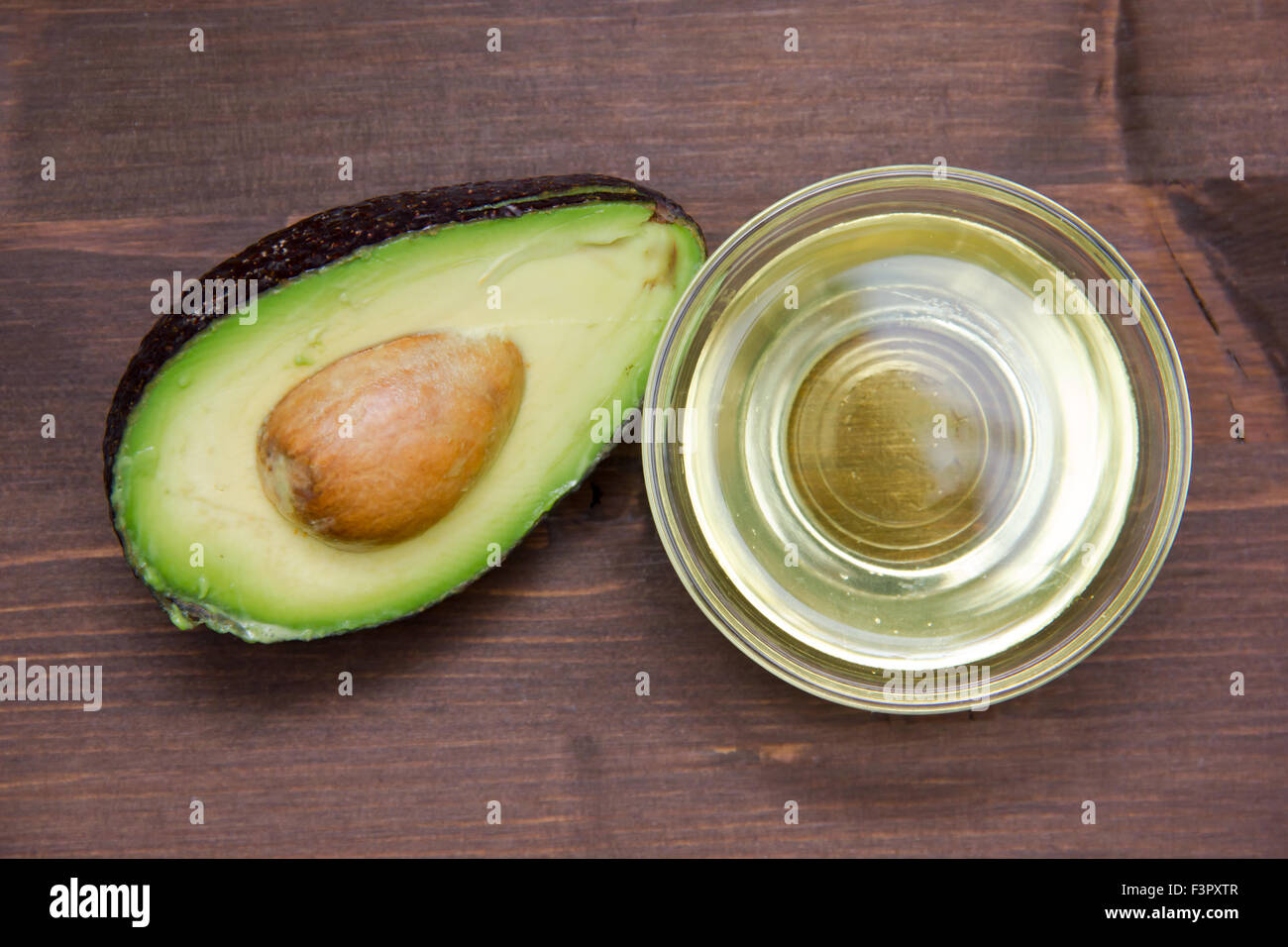 L'huile d'avocat dans un bol sur la table en bois vu de dessus Banque D'Images