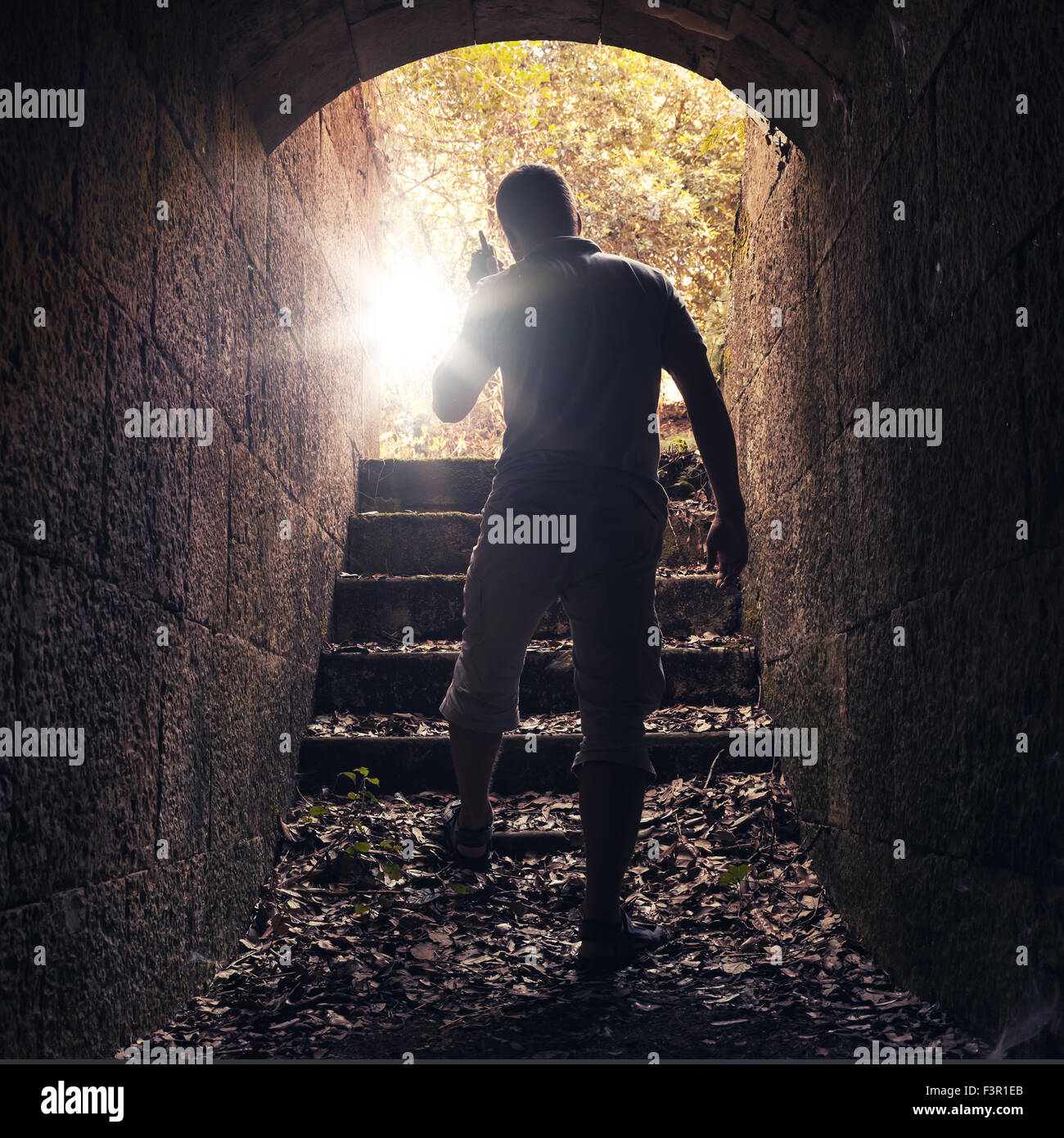 Jeune homme à la radio s'éteint de pierre sombre tunnel, photo aux teintes chaleureuses avec lentille effet glow Banque D'Images