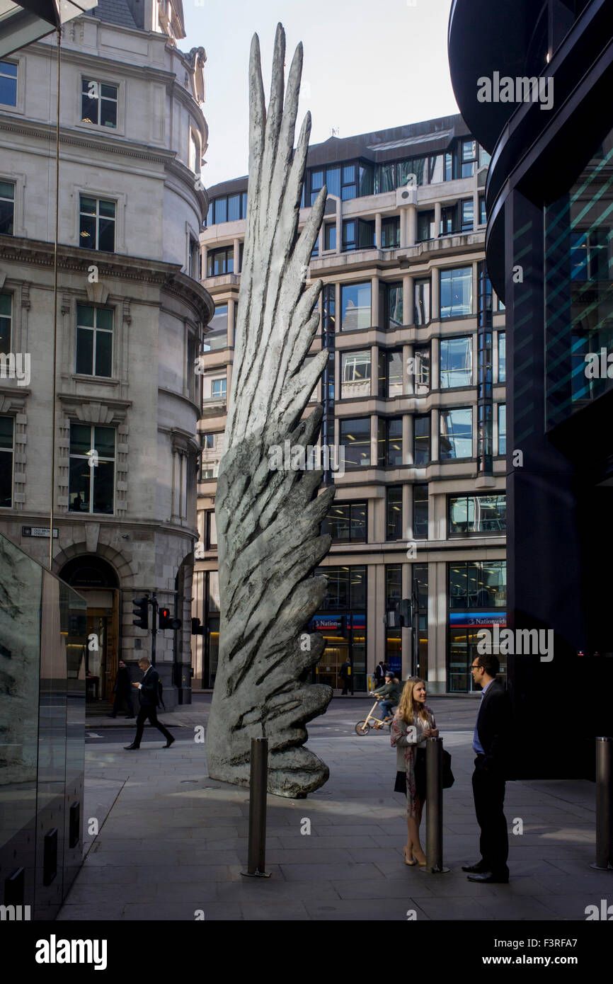 City workers talk sous un artwork d'une aile de bronze à l'heure du déjeuner dans le quartier financier de Londres. Comme la lumière se reflète sur les immeubles de bureaux à proximité, la foule à l'heure du déjeuner devant ce géant des illustrations sur leur façon de réunions et sandwicheries. Les dix mètres de haut est la sculpture en bronze par le président de la Royal Academy of Arts, Christopher Le Brun, commandé par Hammerson en 2009. Elle est appelée 'La Ville' de l'aile et a été jeté par Morris Singer, fondateurs de l'art réputé pour être la plus ancienne fonderie d'art dans le monde. Banque D'Images