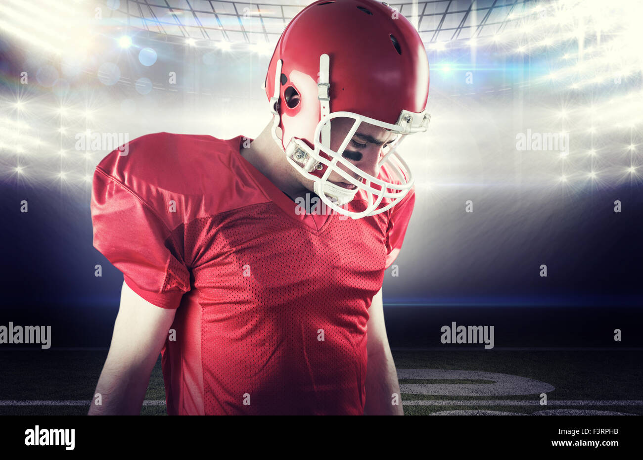 Image composite d'un joueur de football en tenant son casque sur la tête. Banque D'Images