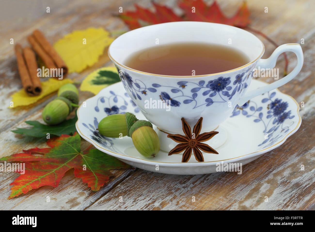 Tasse de thé dans la tasse vintage, l'anis étoilé, les feuilles d'automne et de glands sur la surface en bois rustique Banque D'Images