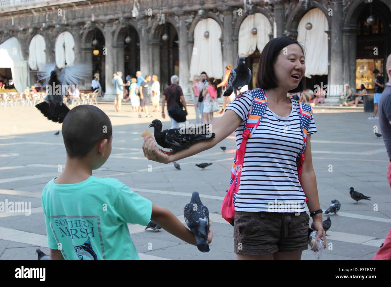 Une femme asiatique pose avec les pigeons dans la place San Marco, Venise Italie Banque D'Images