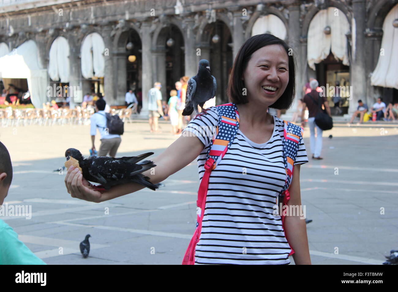 Une femme asiatique pose avec les pigeons dans la place San Marco, Venise Italie Banque D'Images