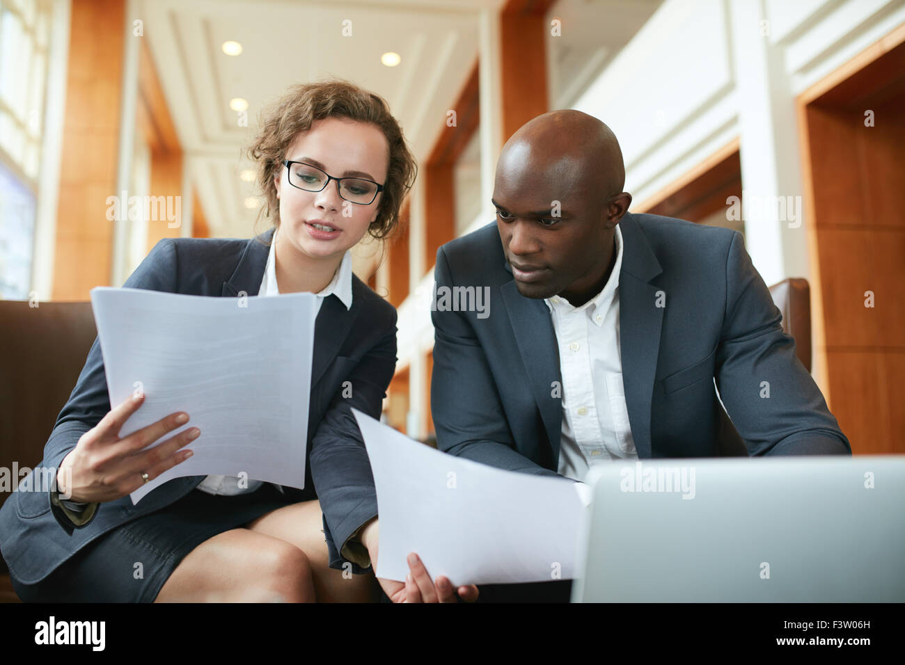 Portrait of young business man and woman sitting in cafe et discuter de contrat. Divers réunion d'affaires dans le hall de l'hôtel Banque D'Images