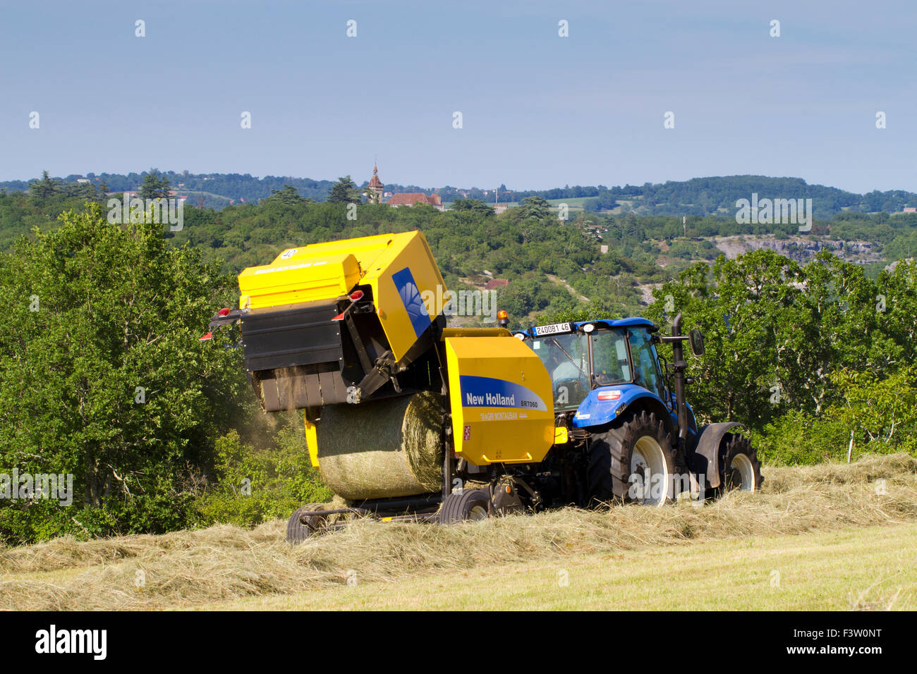 Entrepreneur avec un tracteur New Holland T5.95 et New Holland BR7060 pressage de balles rondes de foin. Près de Rocamadour, Lot, France. Mai. Banque D'Images