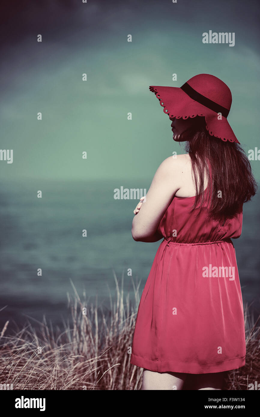 Jeune femme en robe rouge sur la plage Banque D'Images