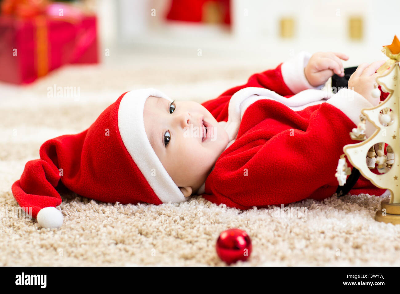 Baby Boy portée Santa holding Christmas ball Banque D'Images